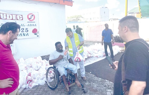 One of the beneficiaries (in wheelchair) receiving a parcel of meat from a volunteer of TUDEC