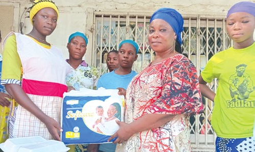 Hajia Kwalebu Fuseinatu Sulemana (2nd from right), Programme Manager, Kunata Voluntary Organisation, presenting a pack of diapers to one of the beneficiaries