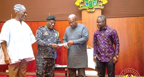 COP Christian Tetteh Yohuno (2nd from left), IGP, presenting the cheque to President John Mahama. With them are Muntaka Mohammed Mubarak (left), Minister for the Interior, and Kwabena Mintah Akandoh, Minister of Health