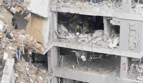 Emergency and rescue workers search for trapped people inside a heavily damaged building