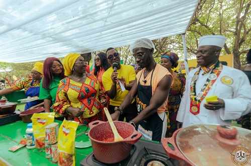 Abla Dzifa Gomashie (2nd from left), Minister of Tourism, Culture, and Creative Arts, and Maame Efua Houadjeto (left), CEO, Ghana Tourism Authority, observing Okyeame Kwame, a Hiplife Artise, prepare a dish at the fair