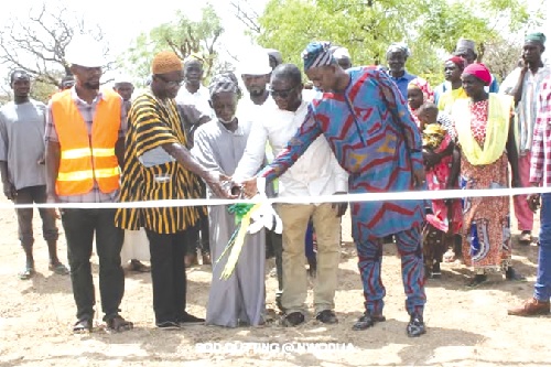 Yahaya Sulemana ( right), Kumbungu District Education Director; Mohammed Awal Sumani Bapio (2nd from right), Executive Director of CALID, supported by community leaders to cut a ribbon to signify commencement of construction
