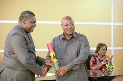 President John Dramani Mahama presenting the scroll of office to Michael Harry Yamson (left), Administrator of the District Assemblies Common Fund