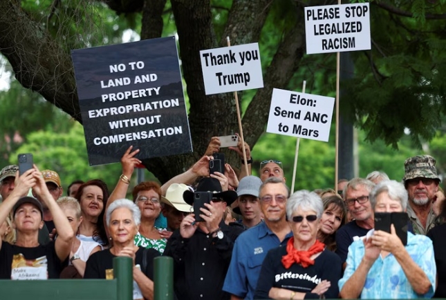 Demonstrators hold placards in support of U.S. President Donald Trump's stance against what he calls racist laws, land expropriation, and farm attacks, outside the American Embassy in Pretoria, South Africa, February 15, 2025. REUTERS