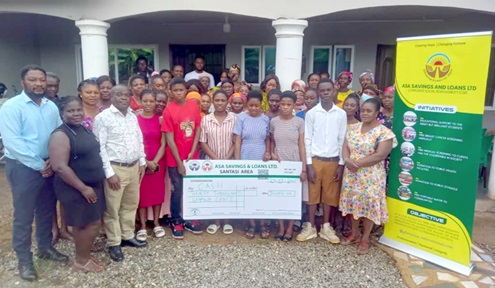 Alexander Opoku Ayitey (left), Santasi Area Manager, Asa Savings and Loans Limited, with the beneficiary students and their parents