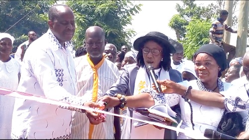 Very Rev. Grace Ansanu (2nd from right), the Superintendent Minister of Gomoa Pinanko Methodist Church, being assisted by Nana Kwesi Essel Okyeahene (left), Gyasehene of Gomoa Wassa, to cut the tape to inaugurate one of the boreholes