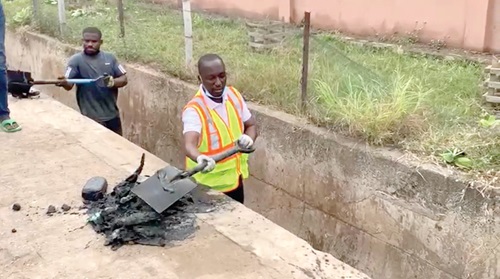 Adamu Musa Kalamu (right), MCE for Ablekuma North, removing refuse from a drain during the clean-up exercise