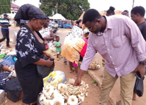 Benjamin Akoto (right), a customer, carefully examining the mushrooms to make his choice