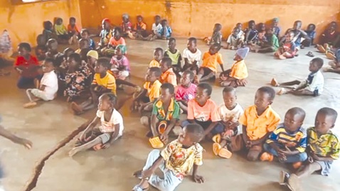Pupils sitting on the bare floor with a visible crack in the classroom Pupils sitting on the bare floor with a visible crack in the classroom