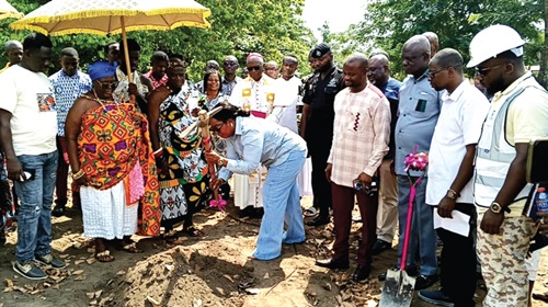 Rita Akosua Adjei Awatey (with pick-axe), Eastern Regional Minister, breaking the ground for construction work to start.