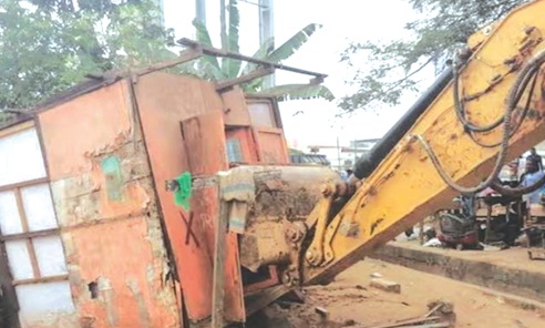 An excavator lifting a shop from its original site An excavator lifting a shop from its original site