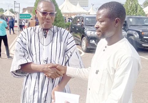 Dr Clement Abas Apaak (left), Deputy Minister for Education, presenting a cash donation to Yussif Abdul Fatawu, the teacher, in Bolgatanga