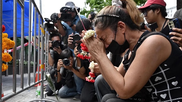 A woman prays for her deceased daughter and her son-in-law