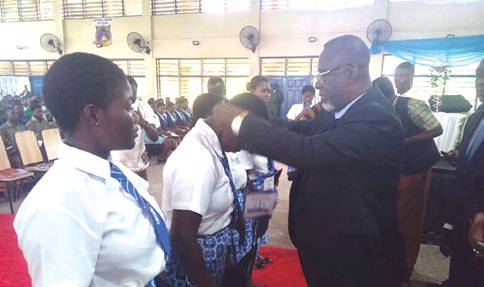 Justice Paul Baffoe-Bonnie, Chief Justice, presenting badges of leadership to officers of Afia Kobi Ampem Girls SHS Justice Club during the event