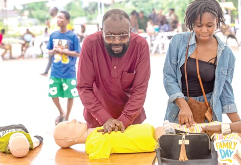 Kwadwo Asamoah-Badu (left), CEO of One Life NGO, performing chest compressions as he demonstrates cardiopulmonary resuscitation to the audience. Standing by him is a volunteer