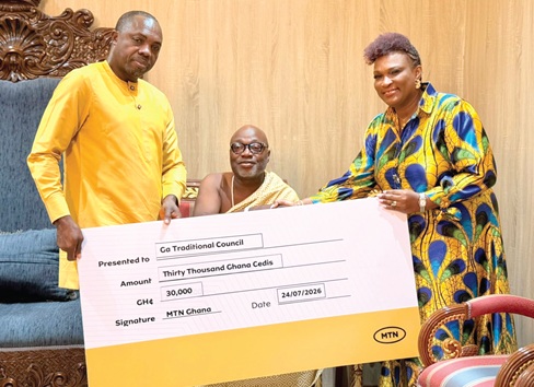 Jemima Kotey-Walsh (right), Chief Customer Experience Officer, MTN Ghana, and Peter Bimpeh (left), Senior Manager, Regional Sales, South East, presenting a dummy cheque to Nii Ahele Nunoo III, Paramount Chief of Abola, during the donation 