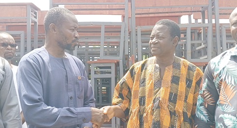 Haruna Abdul-Karim (left), Kpandai DCE, handing over the furniture to Yaw Sarfo, Kpandai District Director of Education