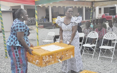 Victoria Amefadzi Yawa Doe (left), District Chief Executive of North Tongu, presenting a cage of chickens to a beneficiary of the project