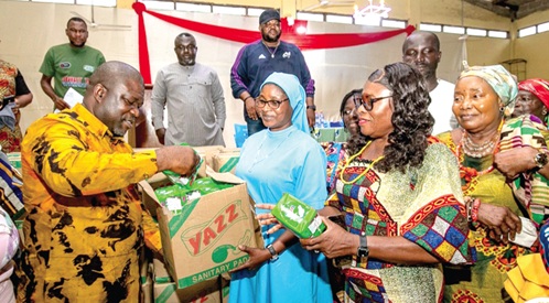 James Gunu (left), Volta Regional Minister, presenting a box of sanitary pads to Rev. Sister Genevieve Afordofe, Headmistress of St Catherine Senior High School, Agbakope, while some stakeholders look on