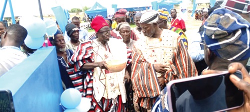 Naba Ayine Akpiisikurugu, Chief of the Pwalugu, holding a calabash to take the ceremonial sip of water to officially inaugurate the borehole. Looking on are elders of the community