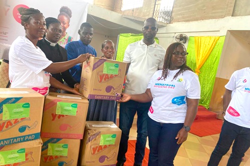 Solomon Azubila (2nd from right), Birim North District Director of Education, presenting some of the sanitary pads to one of the head teachers of the beneficiary schools. With him is Mercy Quansah (right), the Executive Director of Ntiamoah Foundation, and other officials