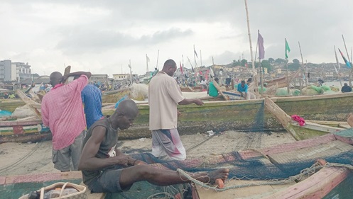 Fishermen mending their nets on a beach in Cape Coast