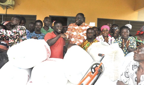 Kingsley Sonu (middle), Agotime-Ziope District Director of Social Welfare and Community Development, presenting the items to Wisdom Yormekpe, Chairman of the Agotime-Ziope PWD Association, while members of the association look on