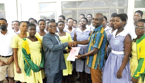 Edem Kofi Kpotosu (2nd from left), MP for Ho Central, presenting the items to Bright Ofori, Volta Regional Director of the Ghana Library Authority, while some students look on