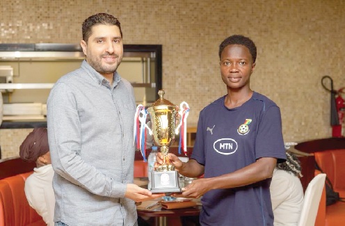 Portia Boakye, captain of the Black Queens, receiving the winner's trophy from the tournament's organisers at the team's hotel