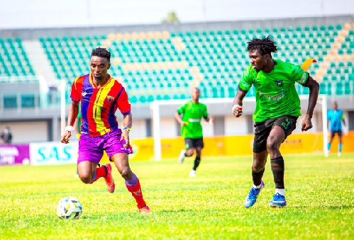 Hearts of Oak’s Martin Karikari bursts forward with the ball under pressure from Basake Holy Stars captain Moses Author (right) during  yesterday's clash in Accra