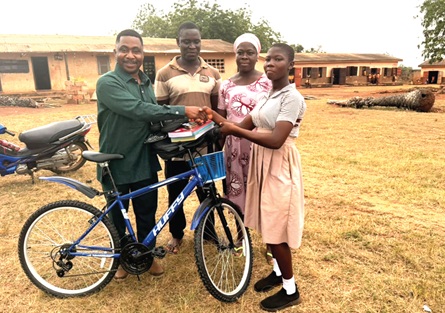 Dr Foster Nanewortor (left) presenting the items to Bethel, as her parents look on
