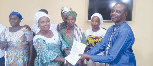 Hannah Talata Asanyuu-re, leader of the women, presenting the petition to Amanah Jojoe John, the Bongo District Coordinating Director, while others look on