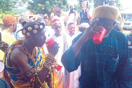 Nana Oppong Adade IV (left), Chief of Bobin, having a taste of the water after the inauguration of the facility