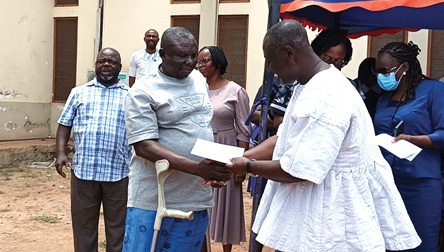 Freeman Tsekpo, Municipal Chief Executive for Ashiaman, handing over a cheque to a beneficiary