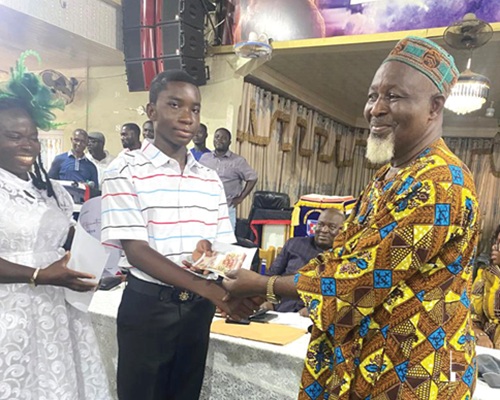 Alhaji Sulemana Adamu (right), Oda Zongo Chief, presenting the overall BECE candidate in the municipality in 2026, Benjamin Sakyi Koranteng with his prize