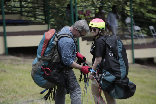 A pilot being assisted to fix his paragliding materials 