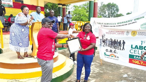 Seth Kwame Acheampong (left), Eastern Regional Minister, presenting a citation to Agnes Amoako, one of the workers who were presented with prizes for their hard work
