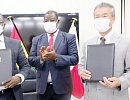 Christian Nti (left), CEO of the GHA, and Toru Watabik, the Managing Director of JFE Engineering, with the signed documents after the formalities, while Kwasi Amoako-Atta, Minister of Roads and Highways, applauds
