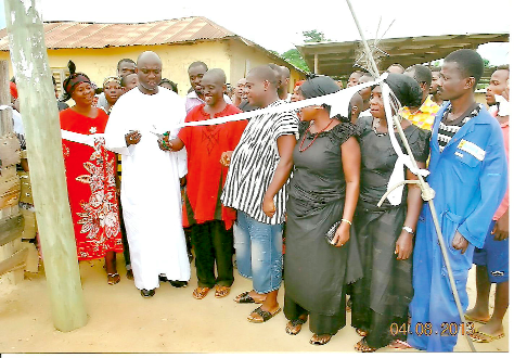 The MP for Abuakwa North, Mr J.B.Danquah-Adu (in robe), inaugurating the project. With him are some of the inhabitants of the village.