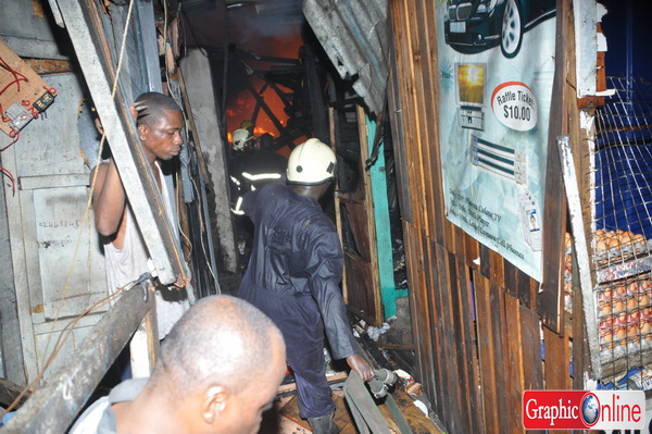 Firemen trying to 'snake' one of their water hoses through the difficult to navigate structures to access the fire. Picture by Nii Martey Botwe/Graphic.