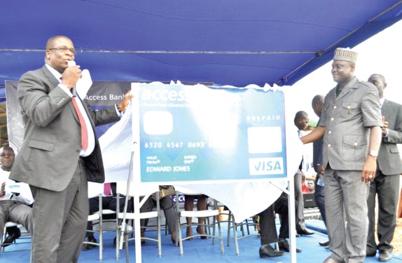 Mr Dolapo Ogundimu, MD, Access Bank (left), being assisted by Alhaji Rauf Tanko (right) to unveil the card.
