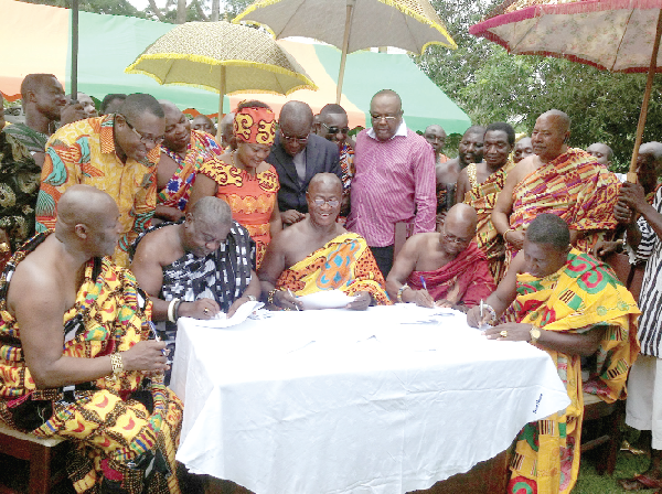 The five divisional chiefs of Okuapeman, including Osahene Kwasi Agyeman (middle), Krontihene of Okuapeman, being joined by the representetive of Nana Otutu Kono (right), Nifahene; Osabarima Enyine Asiedu Okoo Ababio (second right), Benkumhene; Nana Osim Kwatia (left), Gyasehene and Nana Djan Kwasi (second left), Adontenhene of Okuapeman to sign the peace accord. With them are Ms Helen Ntoso (third left standing), Eastern Regional Minister, Mr Ofosu Ampofo (standing left) and Mr Victor Smith (fifth left).