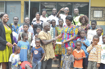 Mr Addai presenting the cash to Mrs Asugnya. With them are some members of the association and the inmates of the home.  Picture: JOHN K. ESSEL