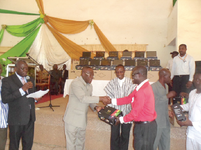 Dr Joe Oteng-Adjei (left) presenting a laptop to a teacher from a beneficiary institution.