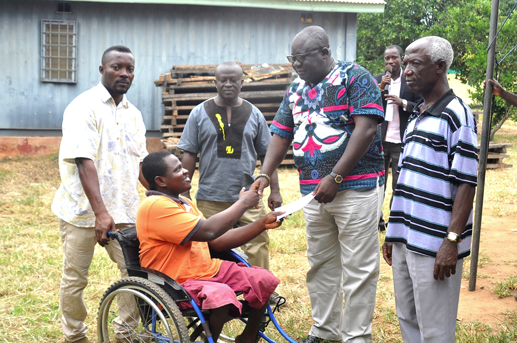 Mr Kwaku Afrifah Yamoah-Ponko (right) the Chief Executive of the Ejisu Juaben Municipal Assembly, presenting a cheque to aPhysically challenged person Mr. Paul Obeng Batey from Fumesua.