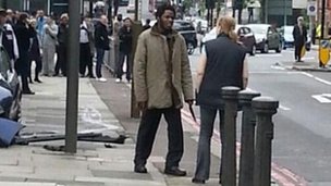 This man was photographed brandishing a knife and speaking to a woman at the scene