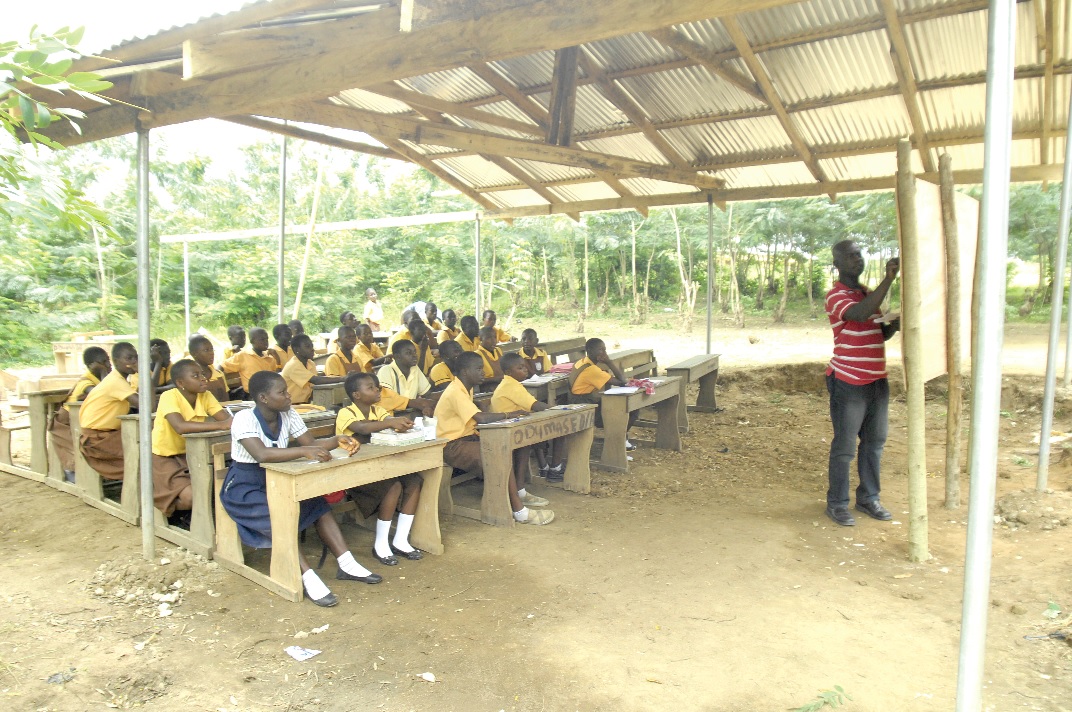 Some students of the Ga Odumase MA1 JHS attend classes under a shed.