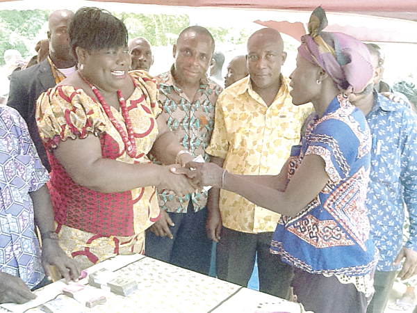 Nana Oye presenting cash to one of the beneficiaries at the Devenu payment point of the LEAP.