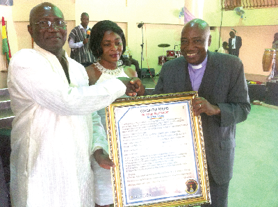 • The Head Pastor of the International Baptist Church, Rev F.C Oteng (right), presenting a citation to Dr Frank A. Odoom. Looking on is Mrs Rosemary Odoom.