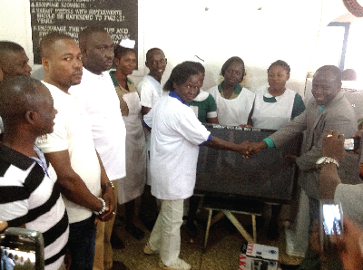 Madam Theresah Nyarko Fofie ( left), a board member of the bank, presenting the items to Very Rev. Adjei  (right). Looking on are Mr Darkwa (third left), board chairman, some staff of the hospital and the bank. Picture: Samuel Duodu.